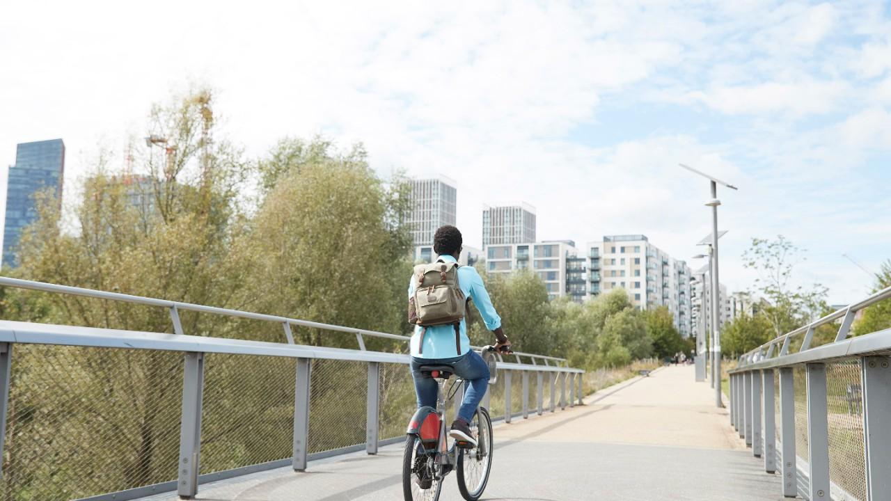 一个女孩骑着自行车过桥进城。